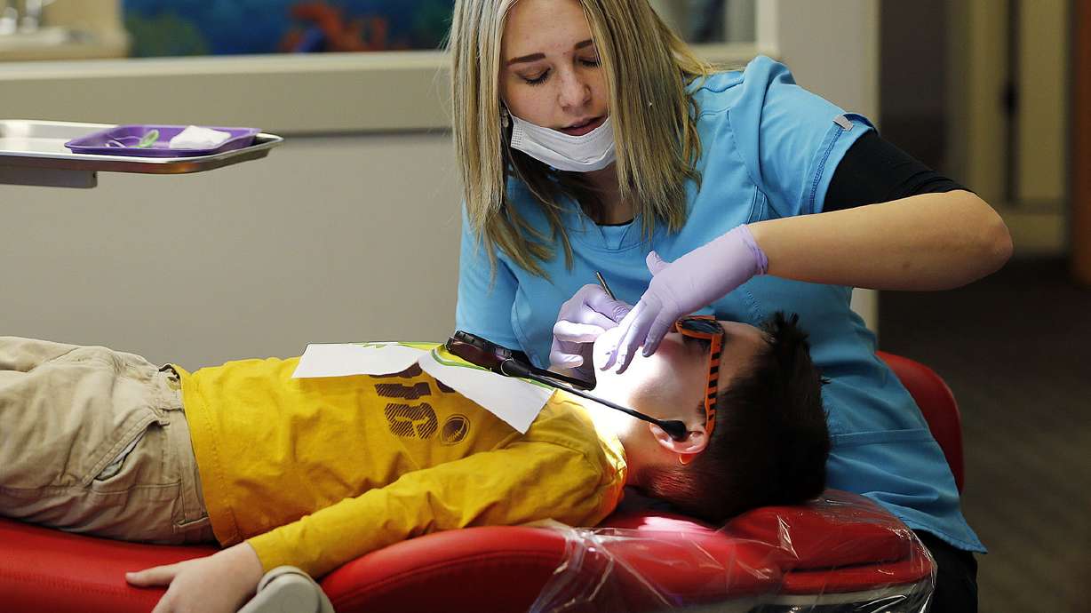 Dental assistant Celeste McHone cleans Dawson McGraw's teeth and treats them with fluoride at Kidz Dental Works in Kaysville on Dec. 5, 2016.