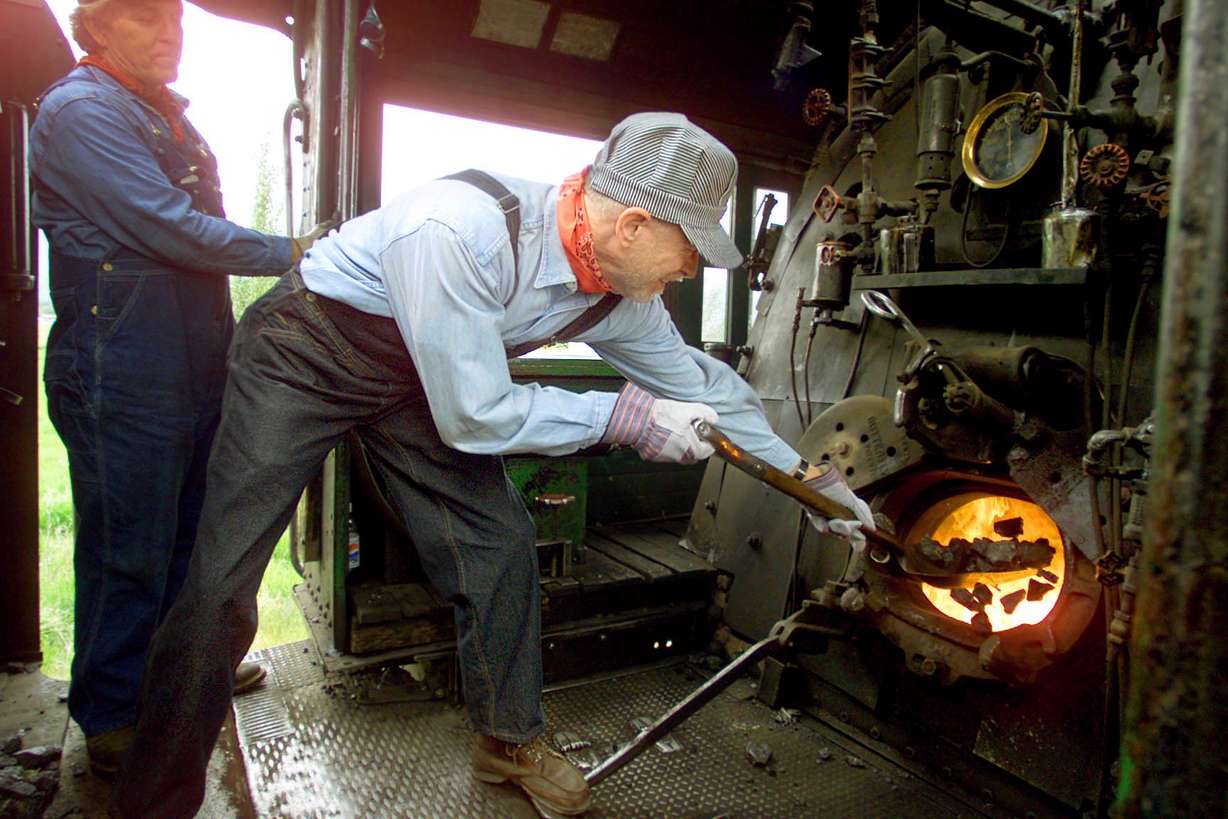 Ken Mcconnell (Conductor) watches over Gib Twyman as he shovels coal in the steam engine of the on the Heber Creeper in 2001. (Photo: Deseret News Archives)