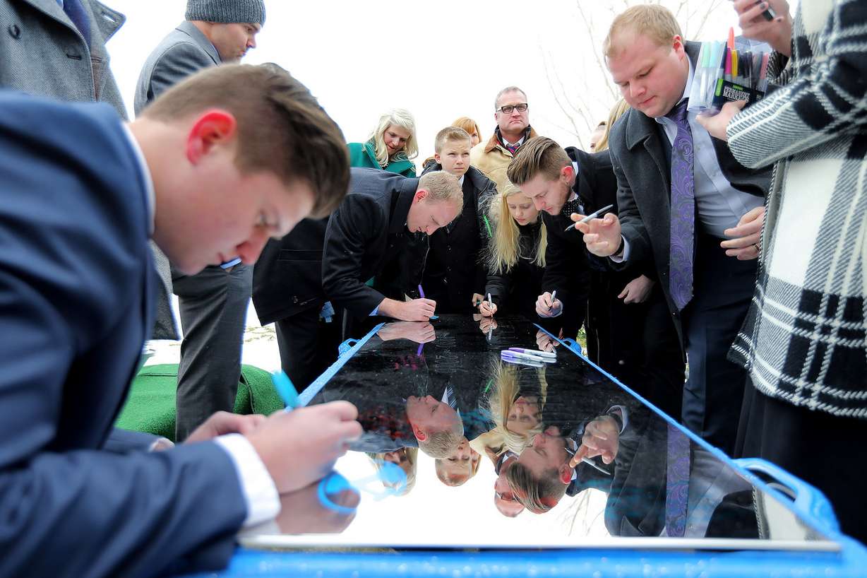 Family members write messages to LaVell Edwards on the top of the vault at Eastlawn Memorial Hills Cemetery in Provo on Saturday, Jan. 7, 2017. (Photo: Scott G Winterton, Deseret News)