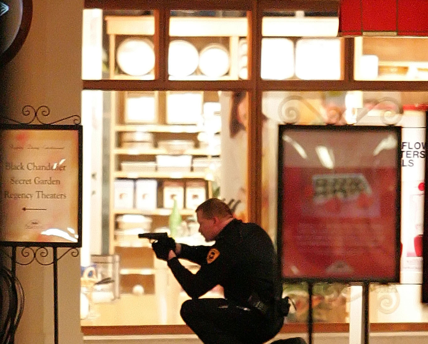A Salt Lake City police officer squats with his gun drawn next to a body inside the Trolley Square Mall, Monday night, Feb 12, 2007. (Photo: Mike Terry, Deseret News, File)