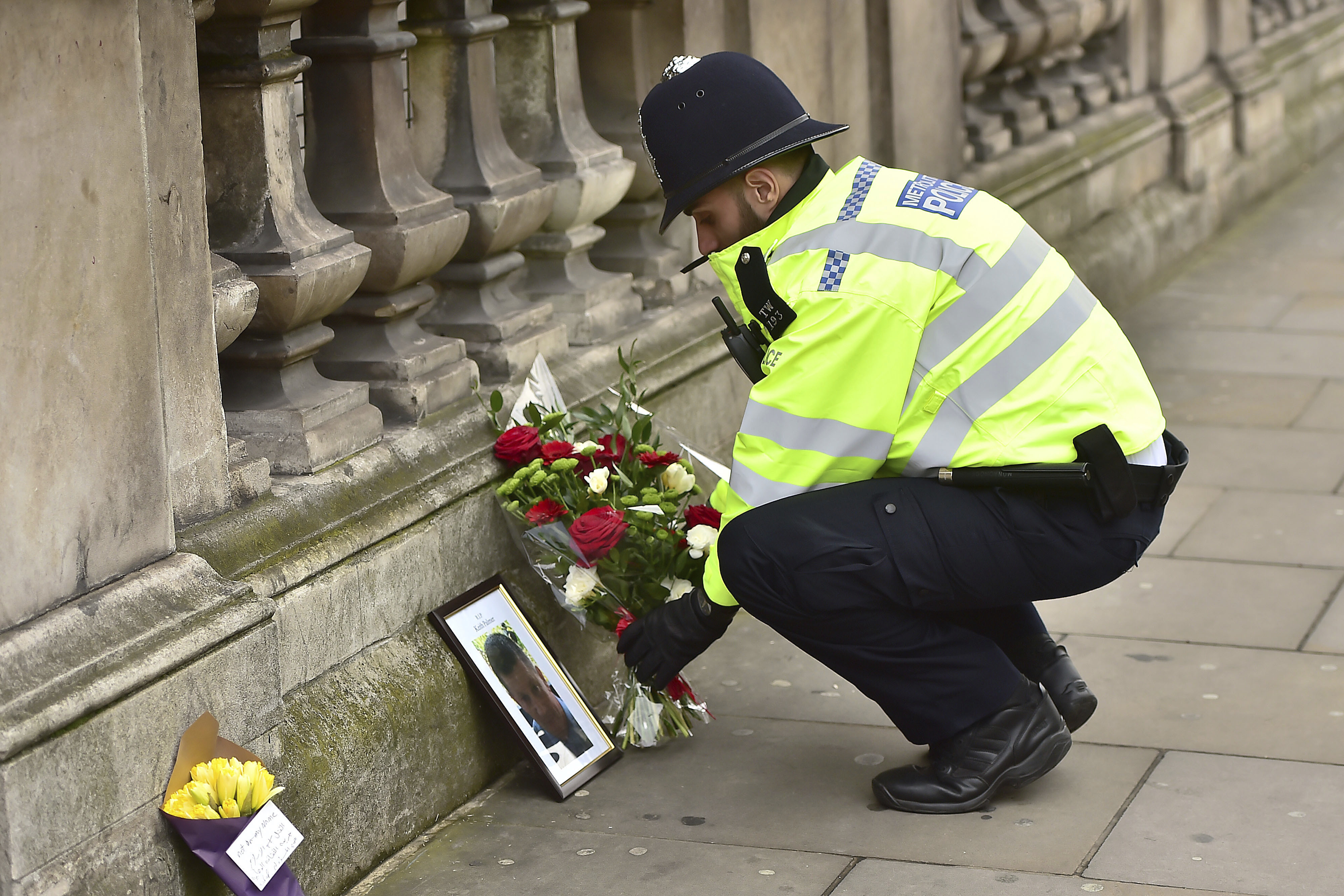 A police officer places flowers and a photo of fellow police officer Keith Palmer, who was killed in yesterdays attack, on Whitehall near the Houses of Parliament in London, Thursday March 23, 2017.