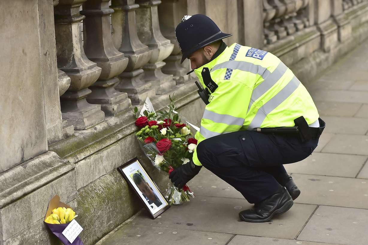 A police officer places flowers and a photo of fellow police officer Keith Palmer, who was killed in yesterdays attack, on Whitehall near the Houses of Parliament in London, Thursday March 23, 2017.