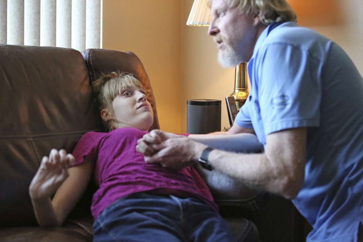 This June 6, 2017, photo, Utah resident Doug Rice, helps his daughter Ashley, 24, during a seizure at their home in West Jordan, Utah. Utah lawmakers balked again this year at joining more than half of all U.S. states and passing a broad medical marijuana law. Rice says Utah's approach means his daughter, who has a genetic condition, is missing out on the one drug that eliminates her frequent seizures. (Rick Bowmer, AP Photo)