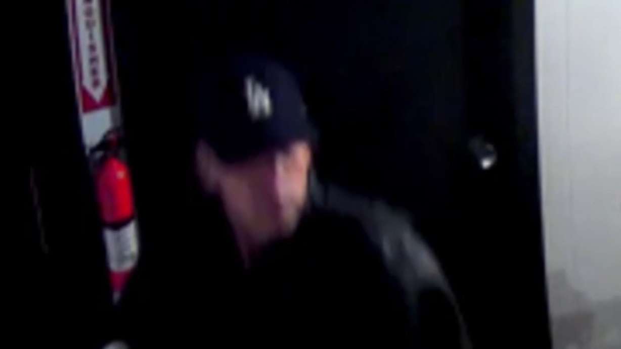 Surveillance video shows a man walking into a photography business Sunday night and immediately yelling in Spanish before punching one of the two people inside. (Security footage)