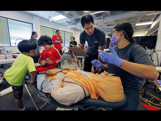 Josi Goodman talks with Derek Tang as she cleans Sumayyah Alsurayhah's teeth during the Junior League of Salt Lake City's annual CARE Fair at Horizonte Instruction and Training Center in Salt Lake City on Friday, July 7, 2017. Alsurayhah's sons, Mutasim Alahmari and Omar Alahmari, are at left. (Photo: Ravell Call, Deseret News)