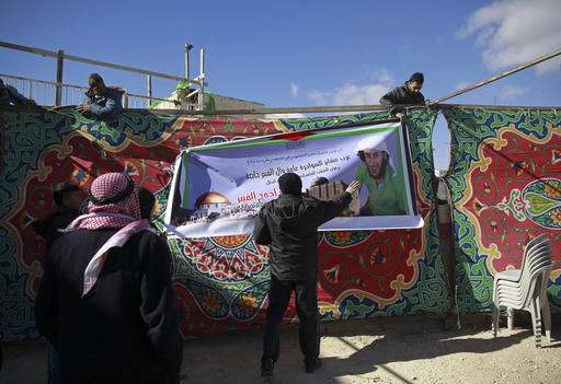 Palestinians hang a banner at a mourning tent being set up for Fadi Qunbar, in east Jerusalem, Monday, Jan. 9, 2017. Qunbar was killed after he drove a truck into a group of Israeli soldiers Sunday killing four and and injuring 17 others. Israeli police said they have arrested nine people, five of them relatives of 28-year-old Qunbar. Banner bearing Qunbar's photo reads, "Arab tribes of Sawahreh and Qunbar, family" and "Palestinian people mourn the martyr hero Qunbar." (AP Photo/Mahmoud Illean)