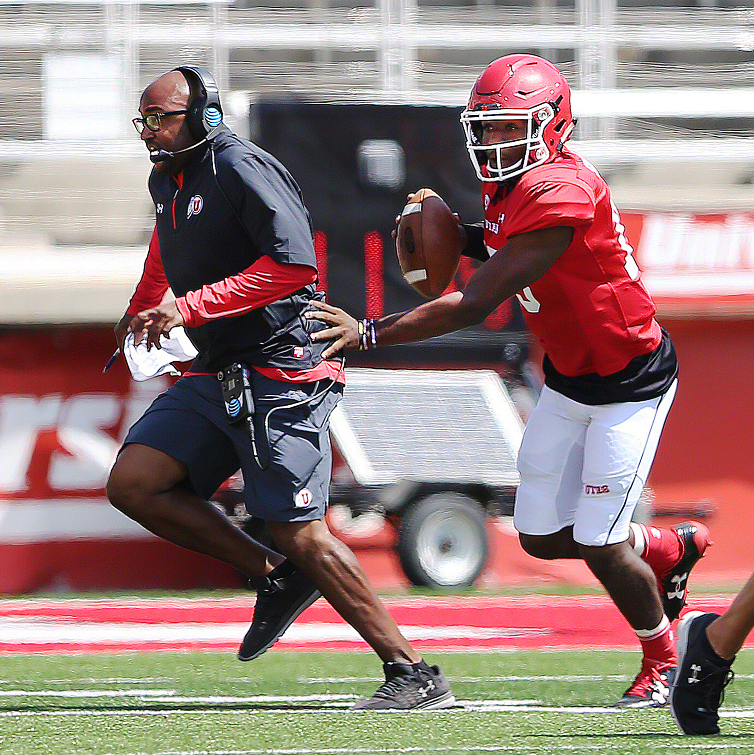 Quarterback Jason Shelley moves running backs coach Kiel McDonald out of the way during a play at University of Utah football practice at Rice Eccles Stadium in Salt Lake City on Saturday, Aug. 5, 2017 (Photo: Scott G Winterton, Deseret News).