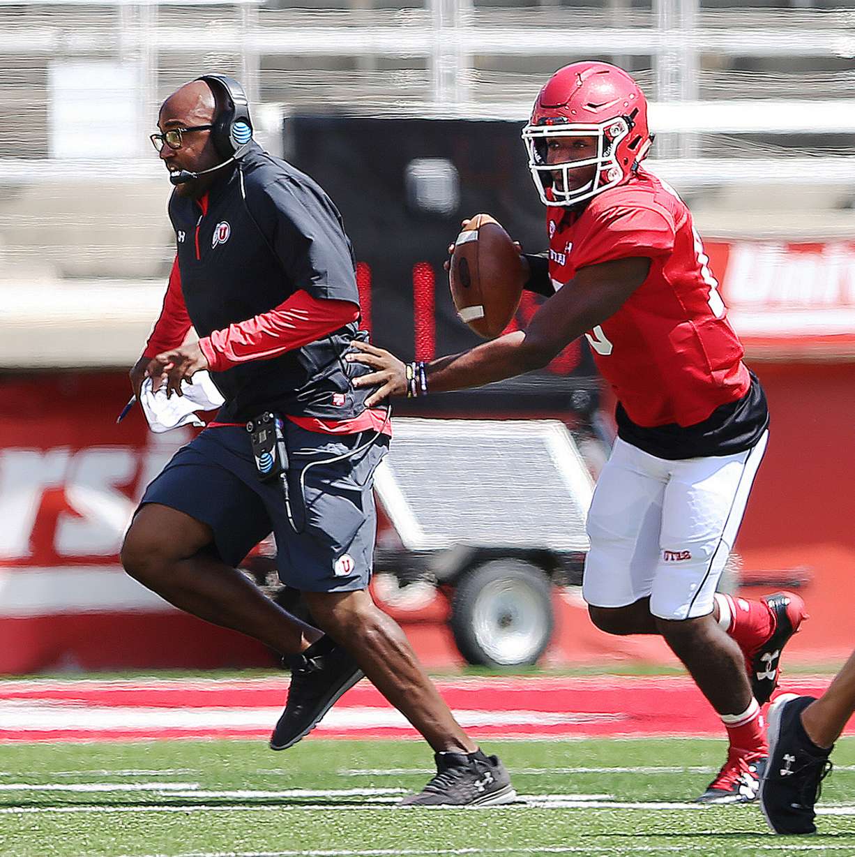 Quarterback Jason Shelley moves running backs coach Kiel McDonald out of the way during a play at University of Utah football practice at Rice Eccles Stadium in Salt Lake City on Saturday, Aug. 5, 2017 (Photo: Scott G Winterton, Deseret News).