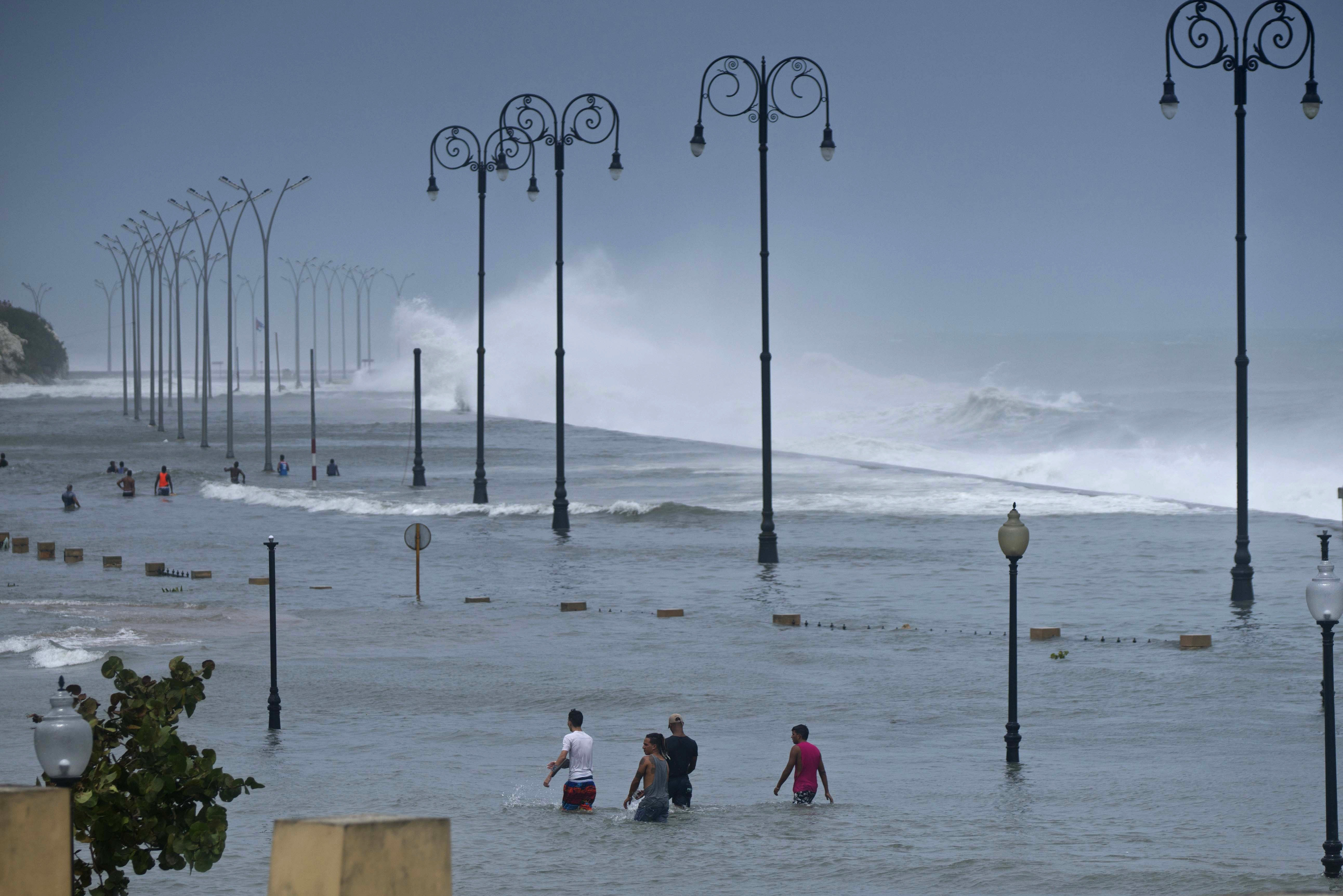 Residents walk on Havana's flooded sea wall as the ocean crashes into it, after the passing of Hurricane Irma in Havana, Cuba, Sunday, Sept. 10, 2017. The powerful storm ripped roofs off houses, collapsed buildings and flooded hundreds of miles of coastline after cutting a trail of destruction across the Caribbean.There were no immediate reports of deaths in Cuba, a country that prides itself on its disaster preparedness, but authorities were trying to restore power and clear roads. (AP Photo/Ramon Espinosa)