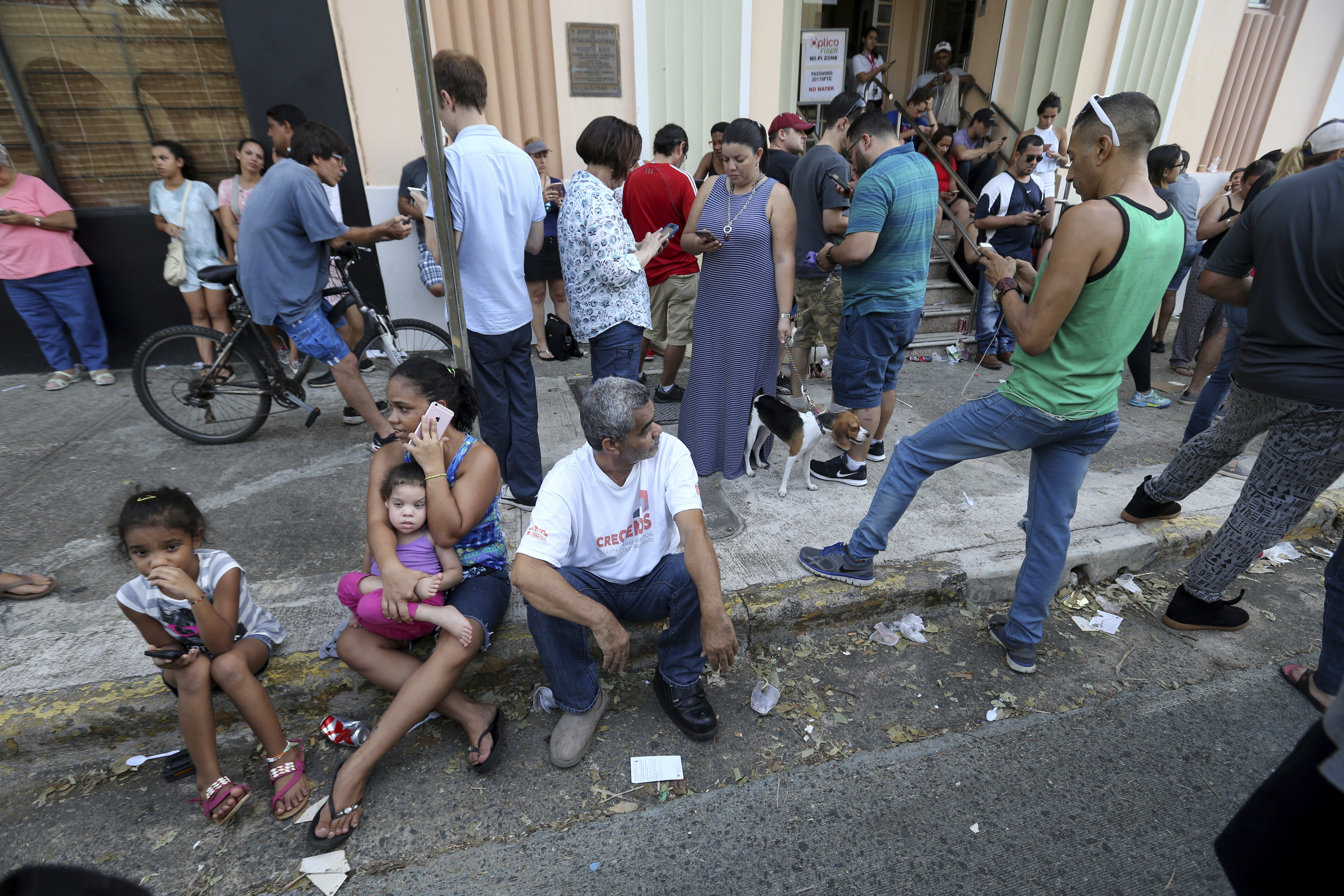 People use their devices to communicate as they congregate on the street at a wifi hotspot in San Juan, Puerto Rico, in the aftermath of Hurricane Maria, Sunday, Sept. 24, 2017. Photo: AP Photo