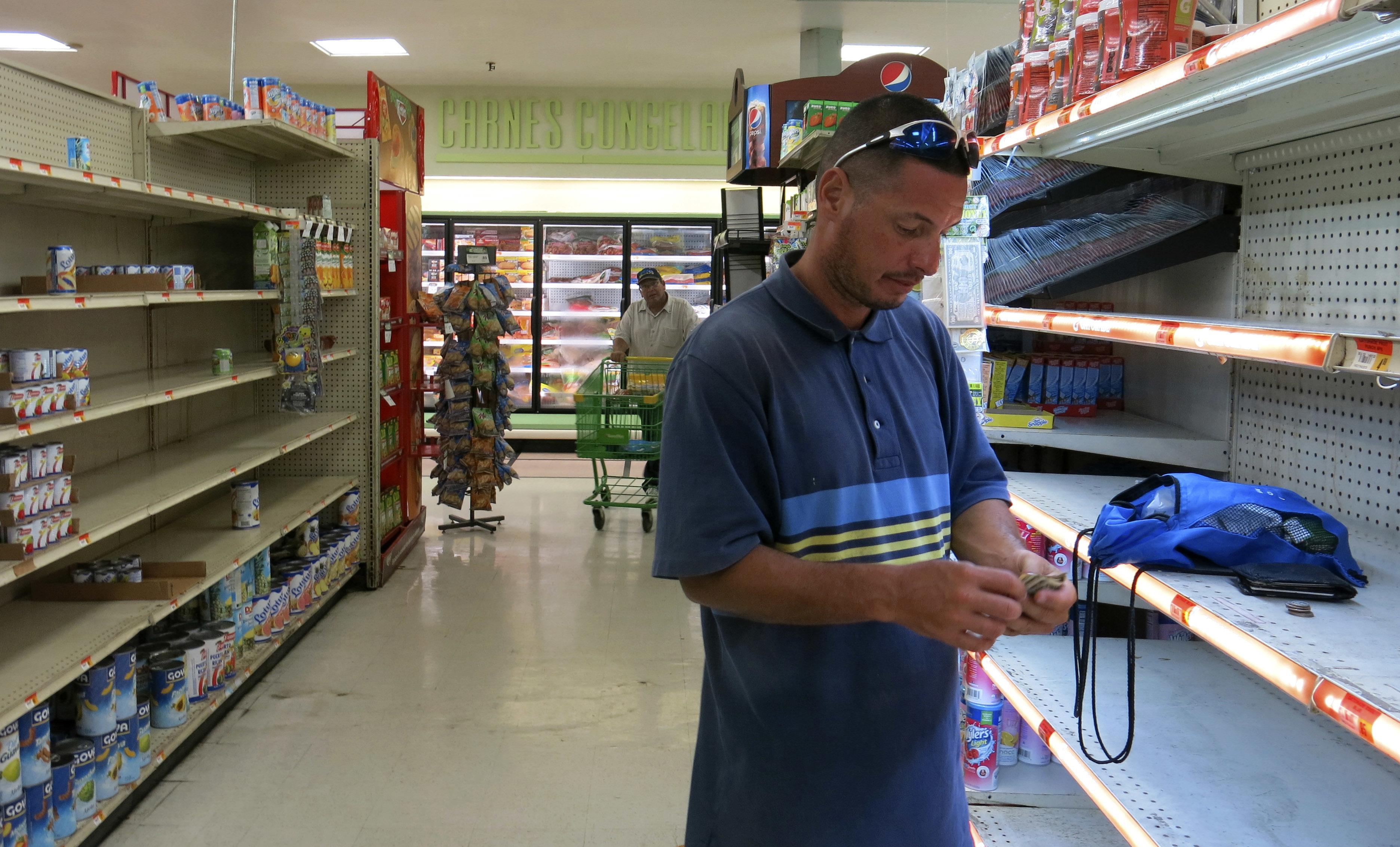 Christian Mendoza counts money in the aisle of a supermarket where he had hoped to buy water but only found cans of juice in San Juan, Puerto Rico, Monday Sept. 25, 2007. Bottled water was gone from stores throughout Puerto Rico in the few stores open. Photo: AP Photo