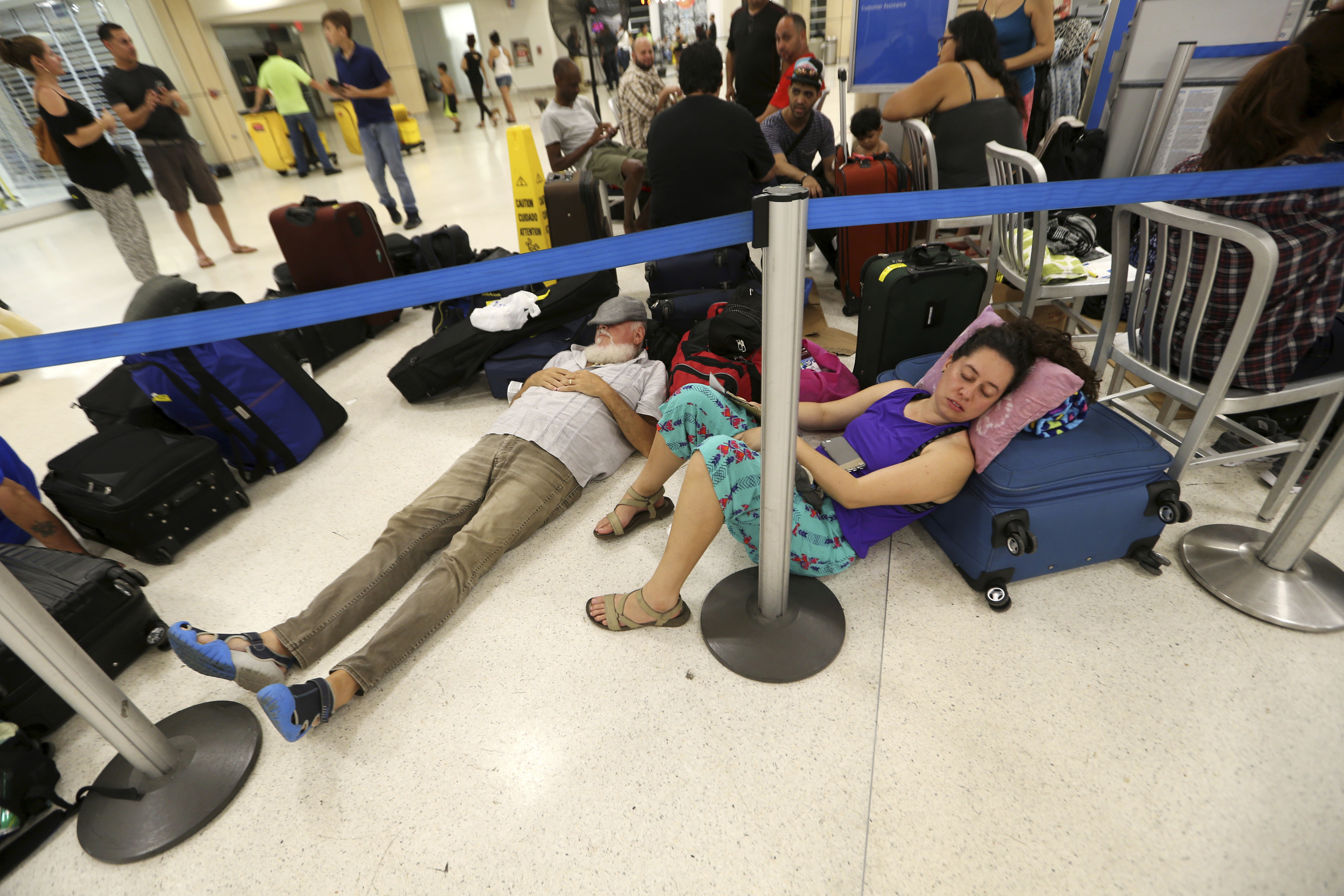 Stranded passengers rest in the main international airport in the aftermath of Hurricane Maria, in San Juan, Puerto Rico, Monday, Sept. 25, 2017. (AP Photo/Gerald Herbert)