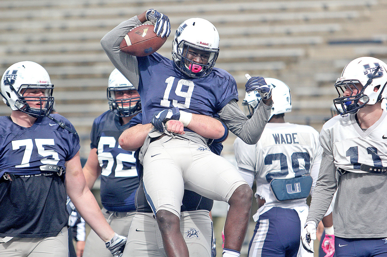 Aggie center Quin Ficklin lifts up wide receiver Ron'quavion Tarver (19) after Tarver caught a touchdown pass during Friday's scrimmage at Maverik Stadium in Logan. (Photo: Jeff Hunter)