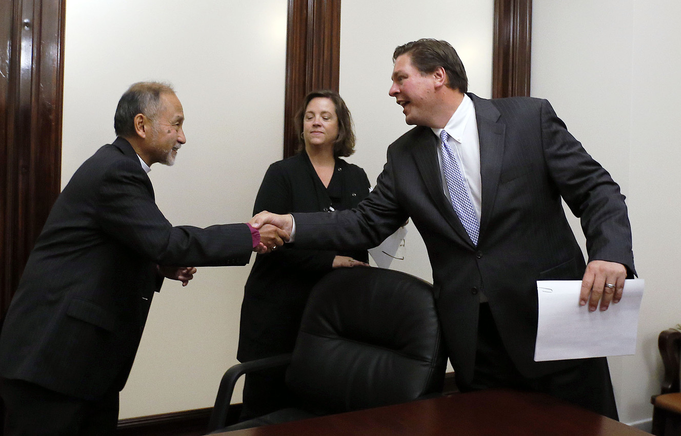 The Right Rev. Scott B. Hayashi, bishop of the Episcopal Diocese of Utah, left, and Alan Omsby, of AARP Utah, shake hands as Dina Blaes, center, looks on following a press conference about the Utah Decides Healthcare ballot proposal. Photo: Ravell Call, KSL