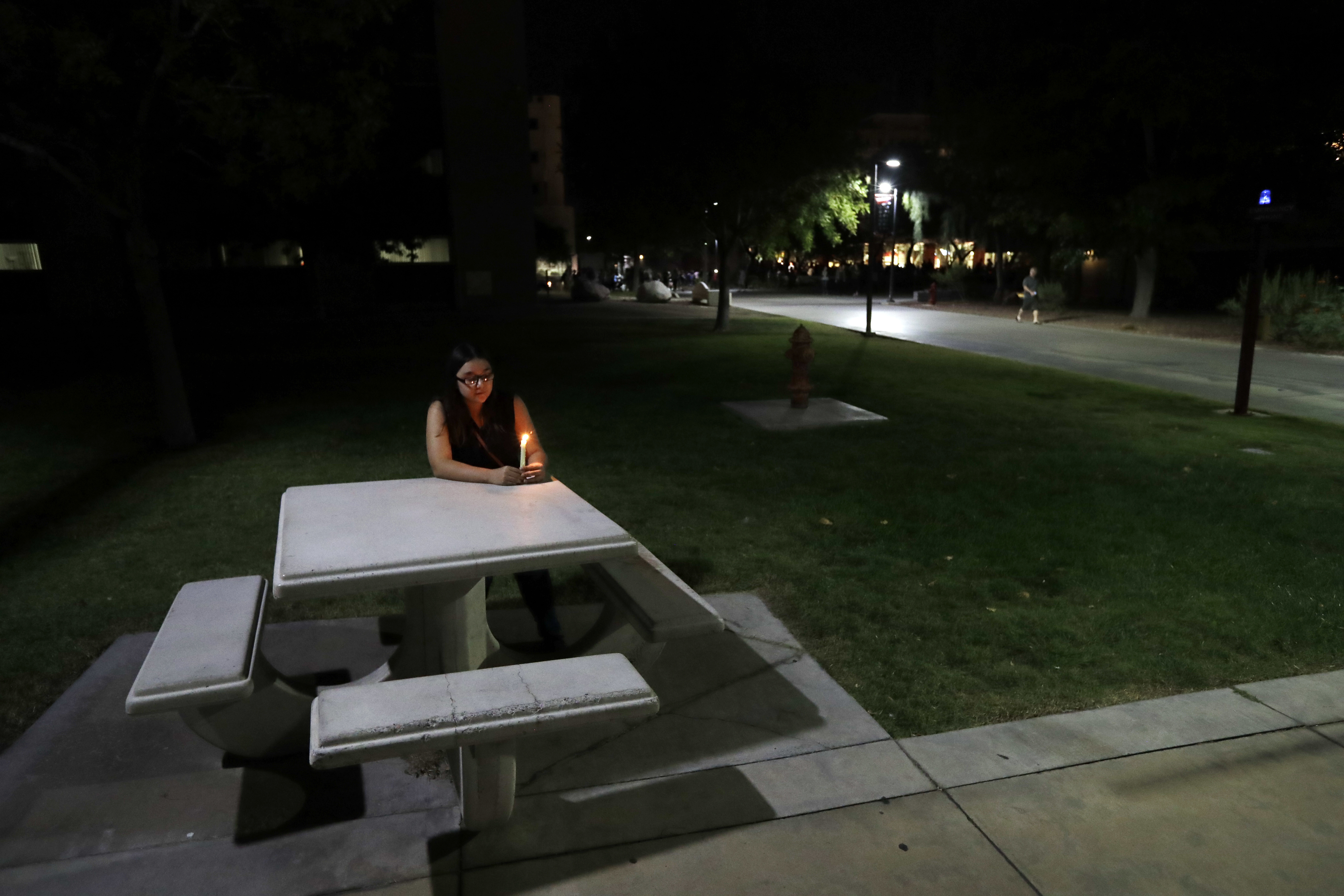 University of Nevada Las Vegas student Johanna Munoz sits at a table with a candle during a vigil Monday, Oct. 2, 2017, in Las Vegas. Photo: AP Photo