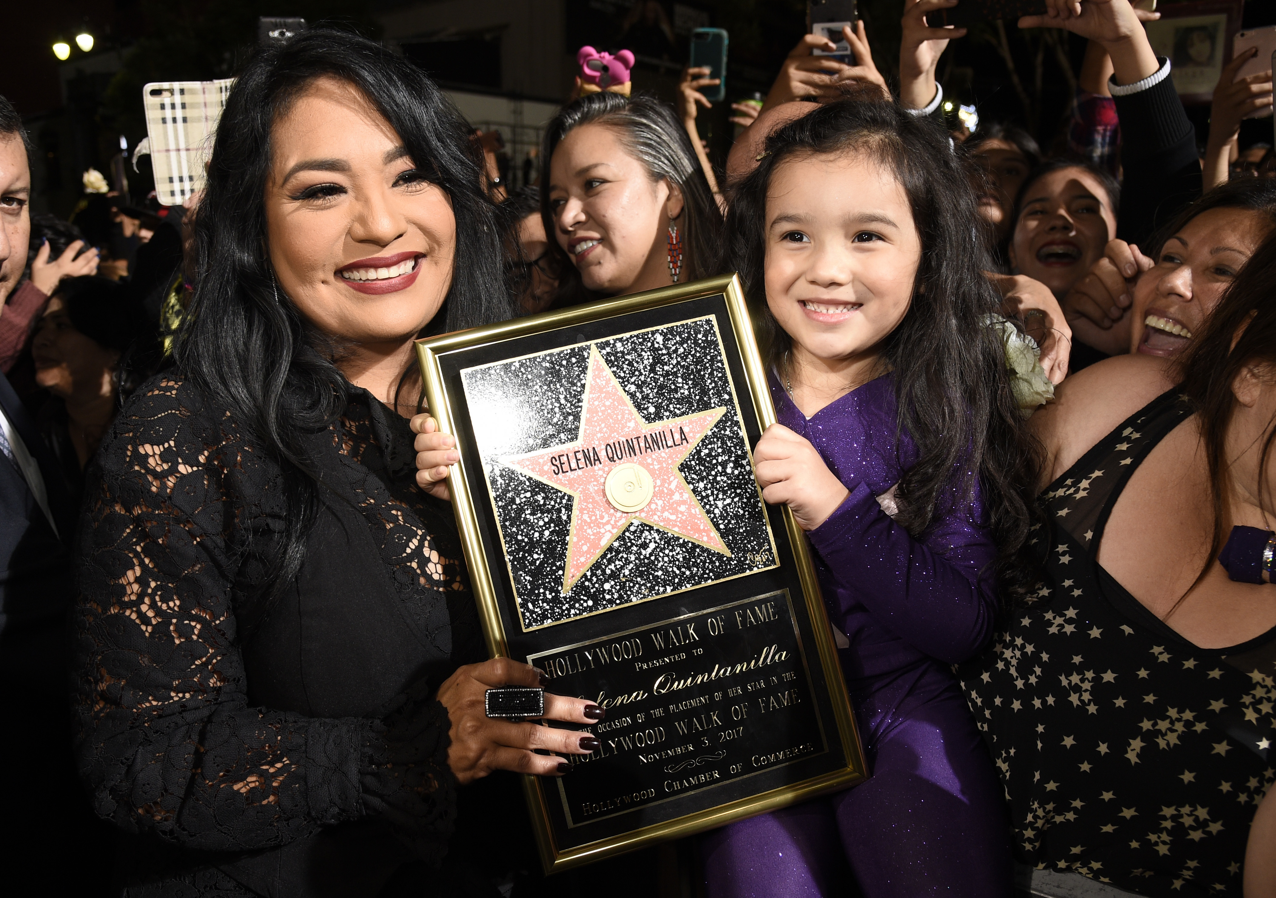 Suzette Quintanilla, left, sister of the late singer Selena Quintanilla, holds a replica of her sister's star on the Hollywood Walk of Fame as she poses with young fan Sammi Corona-Lampa, 4, of Moreno Valley, Calif., following a posthumous star ceremony for Selena on Friday, Nov. 3, 2017, in Los Angeles. (Photo by Chris Pizzello/Invision/AP)