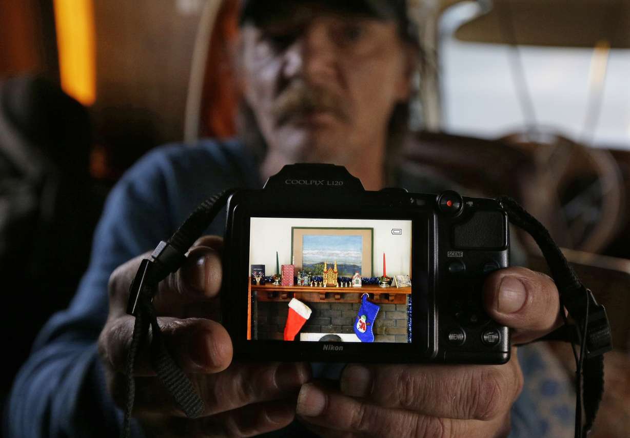 Stanley Timmings poses for a photo as he displays a picture of the Christmas-decorated fireplace mantle he had in the house where he used to live in before becoming homeless. Photo: AP Photo