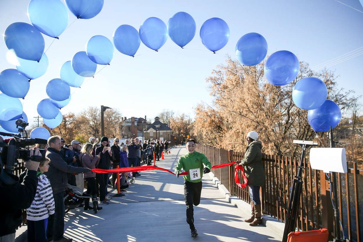 Evan George finishes in first place in a 5K race, cutting the ribbon for the official opening of the Jordan River Trail bridge in Salt Lake City on Saturday, Nov. 18, 2017. (Photo: Spenser Heaps, KSL)