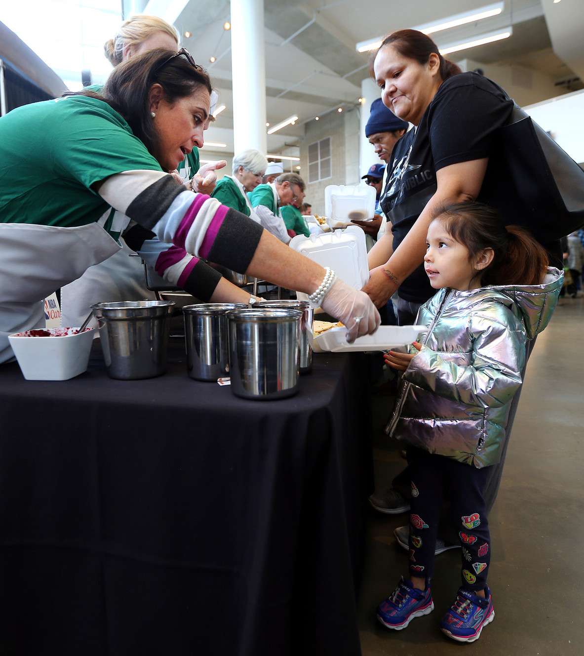 Jenn Andras helps Khloe Clah with her plate as she and her mom Deandra Begay get their food as the Miller family, Larry H. Miller Sports & Entertainment employees and select Salt Lake City Stars players serve food at the 19th annual “We Care - We Share” Thanksgiving Dinner for local homeless and low-income individuals at Vivint Smart Home Arena on Monday, Nov. 20, 2017. (Photo: Scott G Winterton, KSL)