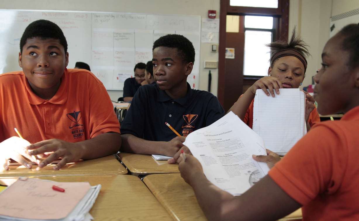 In this Oct. 20 photo, Jamain Lee, center, looks at classmate Andre'veon Mosby at Milwaukee Math and Science Academy, a charter school in Milwaukee. Next to him is classmate Dreamnoel Haynes, with Brianca Williams facing them. Lee has seen his grades improve since he enrolled two years ago from a school where he was bullied and frequently got into fights