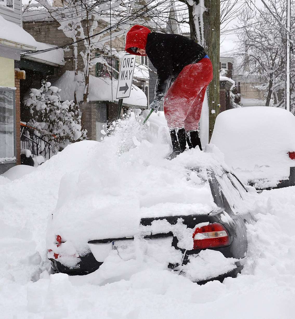 Soledda Hernandez stands on the roof of her car as she brushes off snow in Erie, Pa., Wednesday, Dec. 27, 2017. Snow continues to fall in Erie and surrounding areas that already have seen a record amount of snow over the past few days, prompting a disaster emergency declaration. (Greg Wohlford/Erie Times-News via AP)