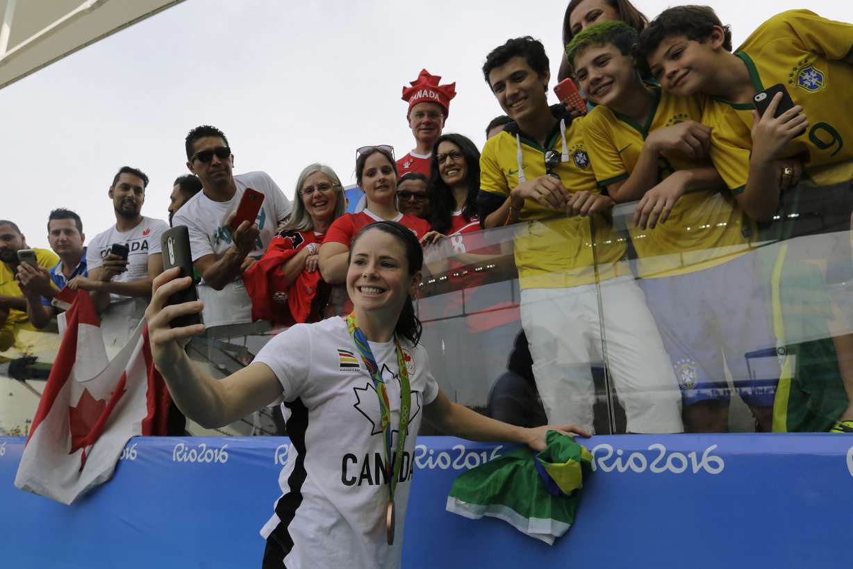 Canada's Diana Matheson, center, takes a selfie with fans after winning the bronze medal in the women's Olympic football tournament at the Arena Corinthians stadium in Sao Paulo, Friday Aug. 19, 2016. (AP Photo, Nelson Antoine)