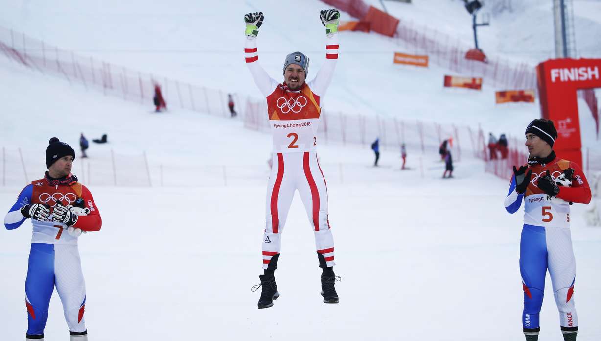 At left, France's Alexis Pinturault, silver, and at right France's Victor Muffat-Jeandet, bronze, watch as Austria's Marcel Hirscher, gold, celebrates during the flower ceremony for the men's combined at the 2018 Winter Olympics. Photo: AP Photo