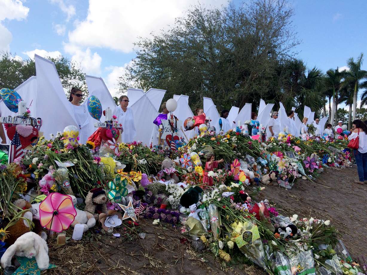 Seventeen people dressed as angels stand Sunday, Feb. 25, 2018, at the memorial outside Marjory Stoneman Douglas High School in Parkland, Fla., for those killed in a shooting on Feb. 14. Organizer Terry Decarlo said the idea originated after the death of University of Wyoming student Matthew Shepard, who was tortured and murdered in 1998. Decarlo said the costumes now travel to disasters and mass shootings around the country. “We want to the survivors to know angels are looking over them and protecting them,” Decarlo said. (AP Photo:Terry Spencer)