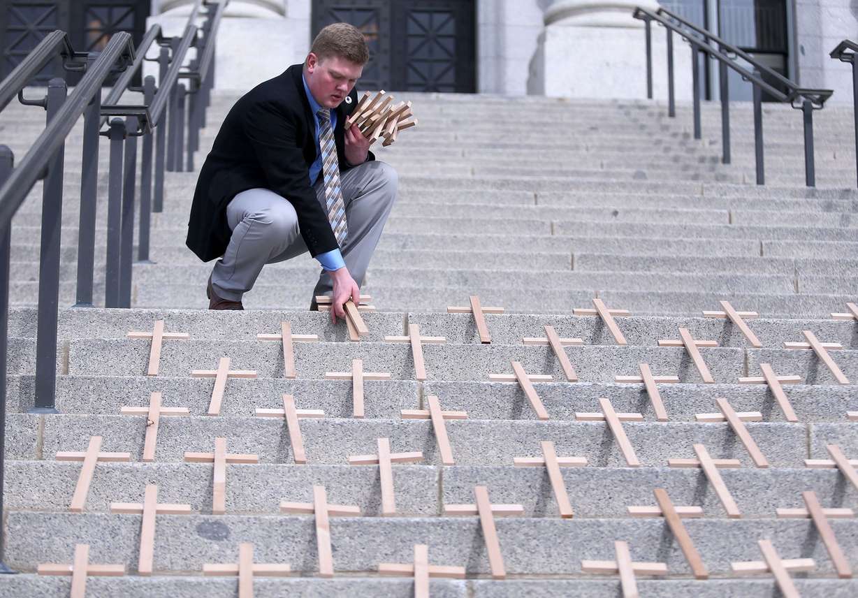 Matt Grooms, southwest regional director for Students for Liberty, picks up crosses representing the 500 students killed in school shootings in the past 50 years on the steps of the Capitol in Salt Lake City on Tuesday, Feb. 27, 2018. (Photo: Kristin Murphy, KSL)