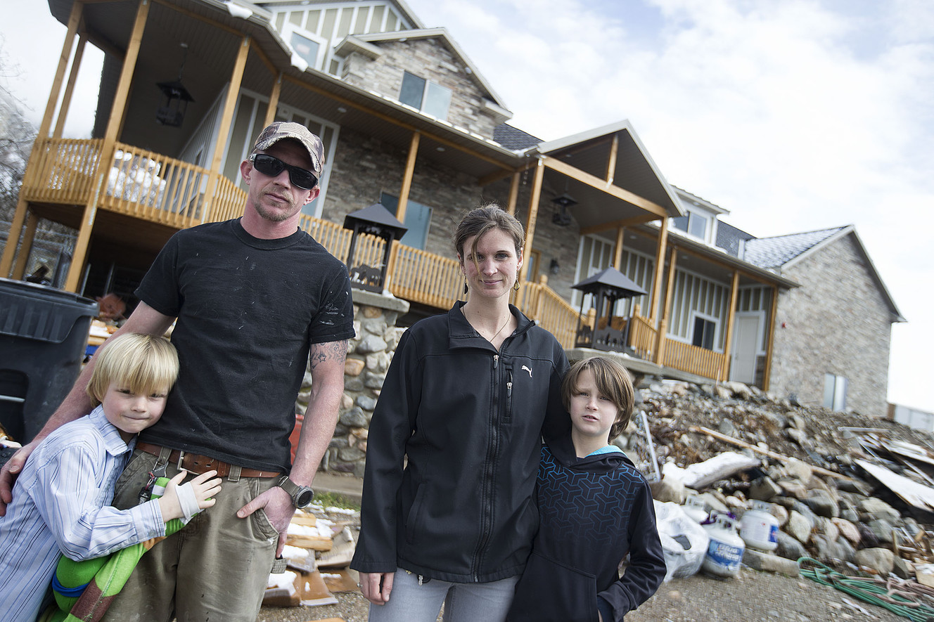 Reese, Ben, Jessi and Corbin Leavell stand in front of their home in Willard on Thursday, March 15, 2018. The home was destroyed in a May 2017 fire and the family has rebuilt it. Jessi Leavell believes a jurisdictional argument between fire departments caused a delay in the fire being completely extinguished thus resulting in the house burning to a complete loss. (Photo: Laura Seitz, KSL)