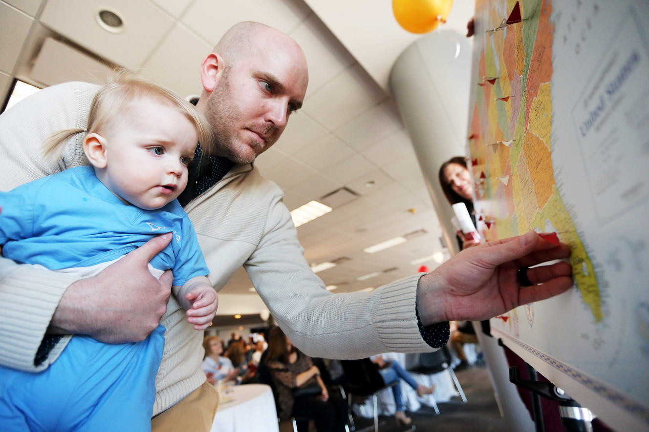 Thomas Lawyer holds his daughter Mia as he puts a pin in a map showing that he is going to study emergency medicine at the Florida Hospital of Orlando. Fourth-year medical students find out where they will conduct their residencies at a reception in the Tower at Rice-Eccles Stadium in Salt Lake City on Friday, March 16, 2018. (Photo: Scott G Winterton, KSL)