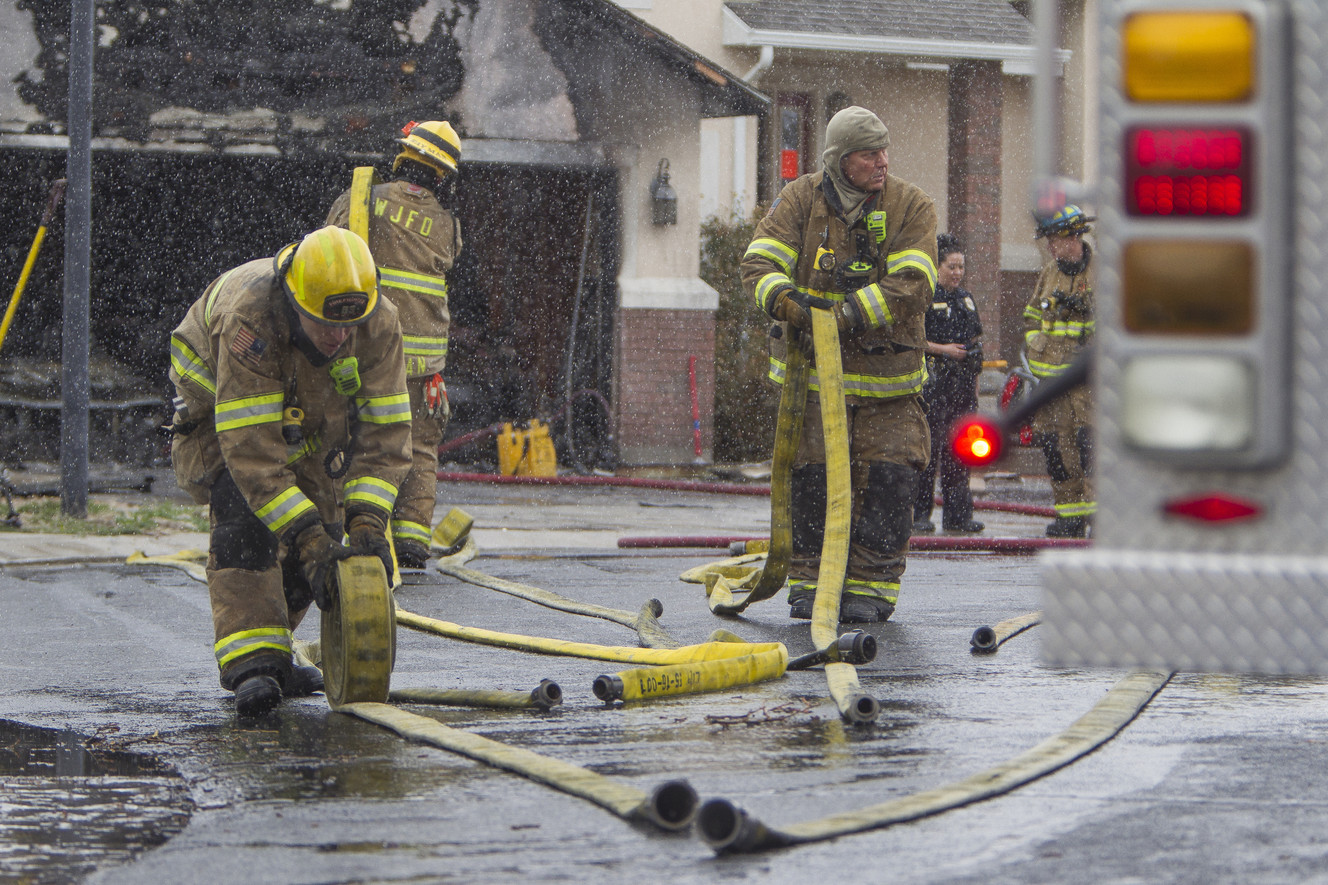 West Jordan firefighters Reedy and Steele roll up hose after responding to a structure fire near Aire and Lena drives in West Jordan on Saturday, March 17, 2018. (Photo: Jacob Wiegand, KSL)