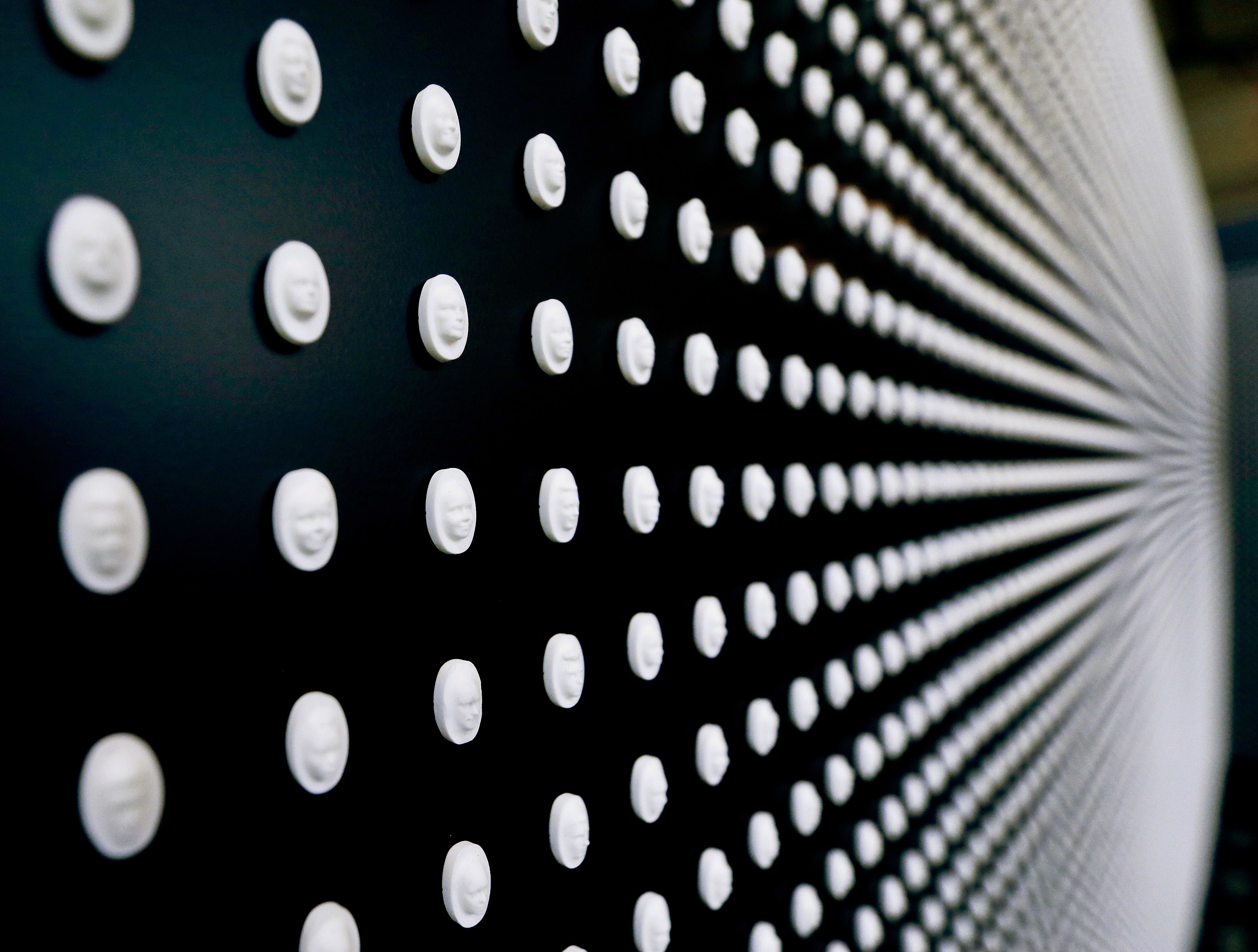 A portion of the 22,000 pills with faces carved into them are on display in a memorial by the National Safety Council to the victims of the opioid epidemic at the University of Pittsburgh, Monday, Jan. 29, 2018, in Pittsburgh. The exhibit featuring the wall with the carved medicine pills, each representing the face of someone who fatally overdosed, was launched in Chicago in November, 2017. Pittsburgh is the first stop on a nationwide tour. (AP Photo/Keith Srakocic)