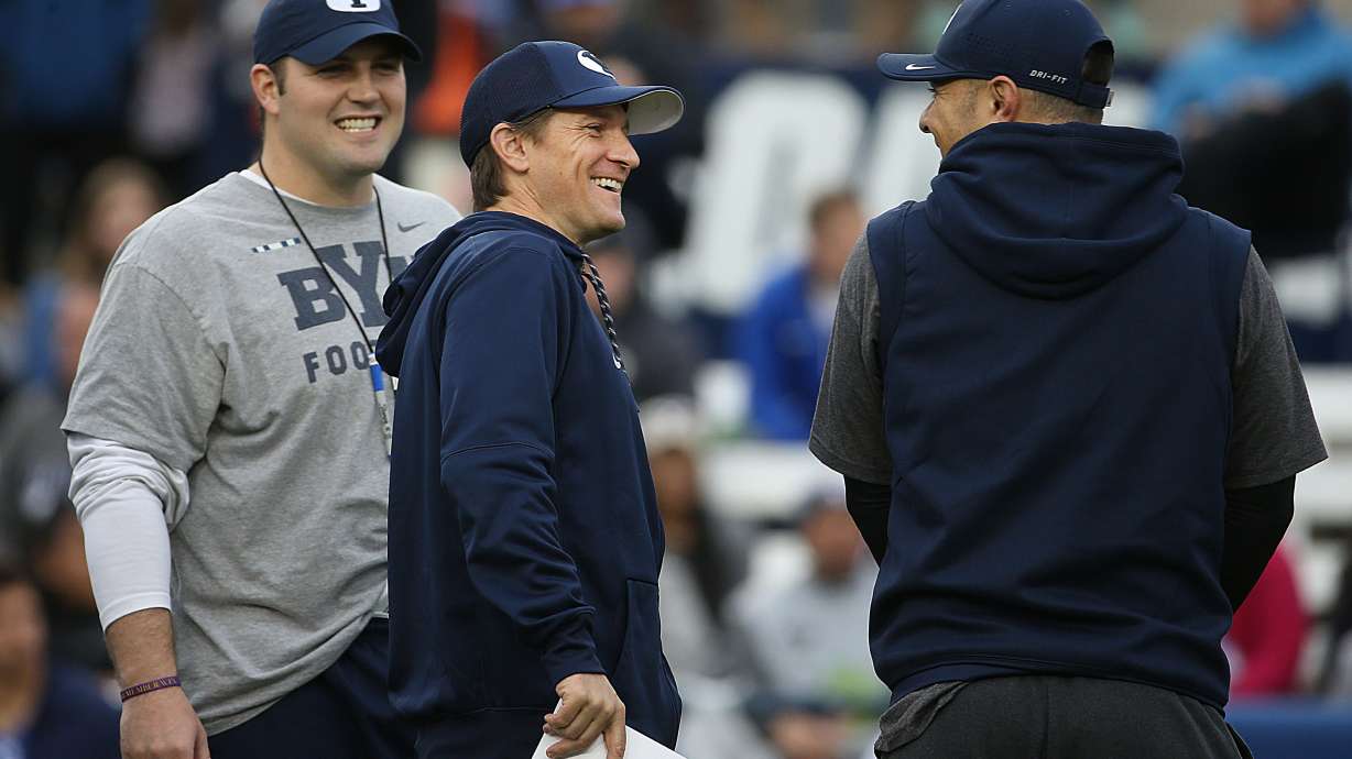 Offensive line coach Ryan Pugh, left and QB coach Aaron Roderick laugh with safeties coach Preston Hadley before the Blue-White game at LaVell Edwards Stadium in Provo on Saturday, April 7, 2018.