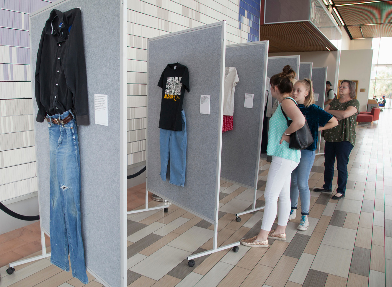 In this April 2, 2018, photo, representatives from the Dove Center and the DSU Women's Resource Center display clothes worn by sexual assault victims in a project titled "What Were You Wearing?" The new exhibit at Dixie State University showcases the clothes sexual abuse victims were wearing at the time of their assaults to dispel the myth that a person’s clothing justifies or condones the acts of sexual violence. (Chris Caldwell/The Spectrum via AP)