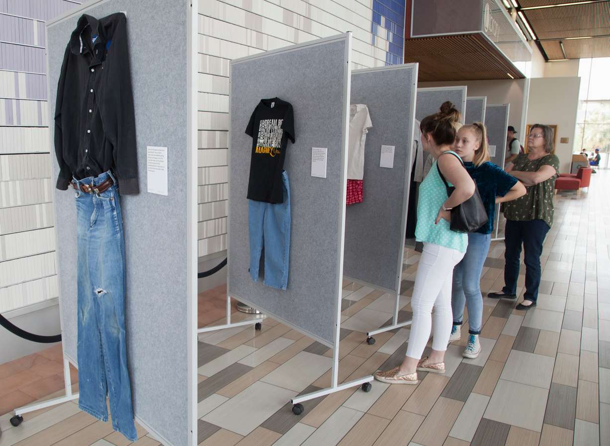 In this April 2, 2018, photo, representatives from the Dove Center and the DSU Women's Resource Center display clothes worn by sexual assault victims in a project titled "What Were You Wearing?" The new exhibit at Dixie State University showcases the clothes sexual abuse victims were wearing at the time of their assaults to dispel the myth that a person’s clothing justifies or condones the acts of sexual violence. (Chris Caldwell/The Spectrum via AP)