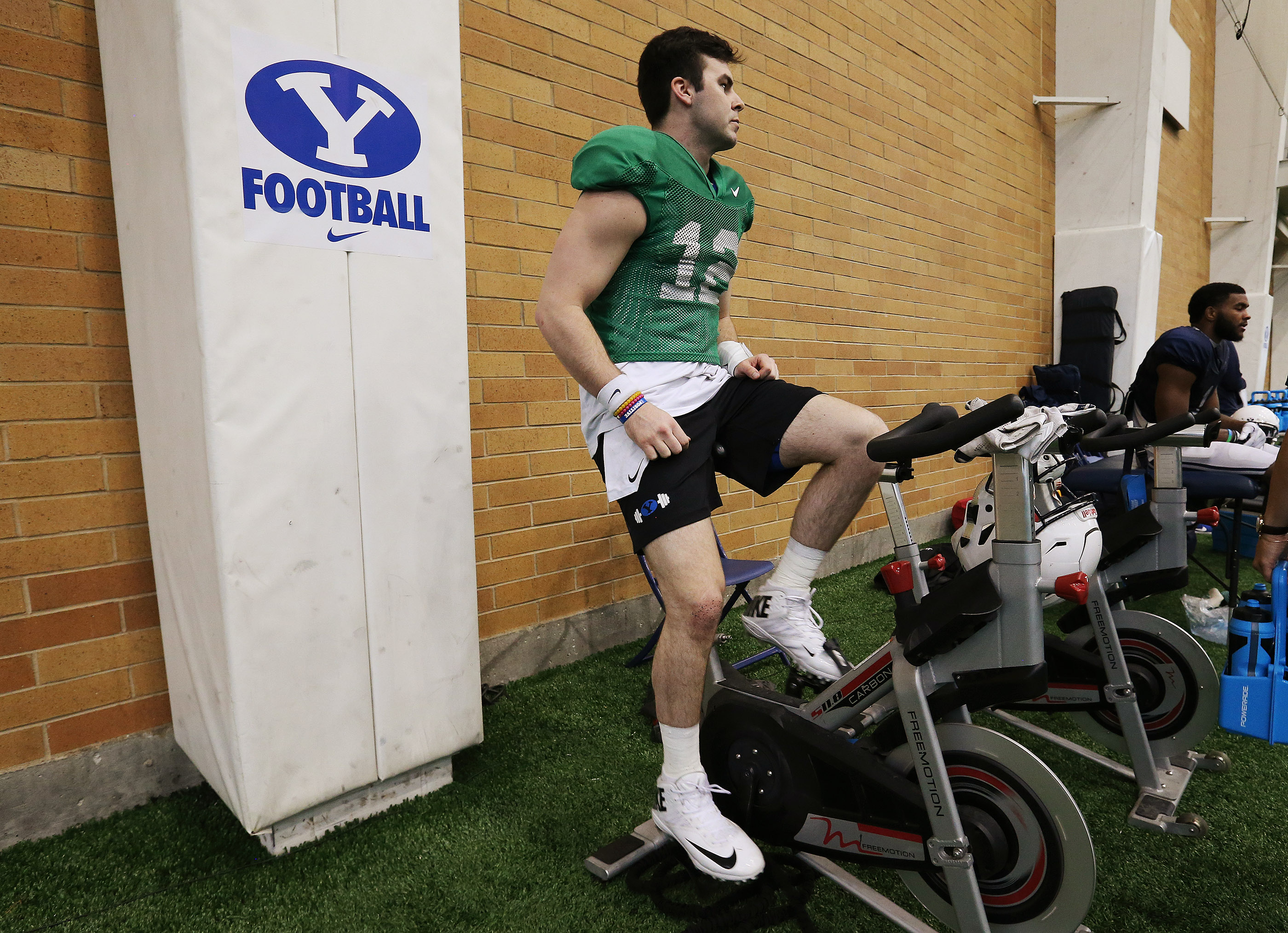 Brigham Young Cougars quarterback Tanner Mangum (12) rides a bike after an intersquad scrimmage in Provo on Friday, March 23, 2018.