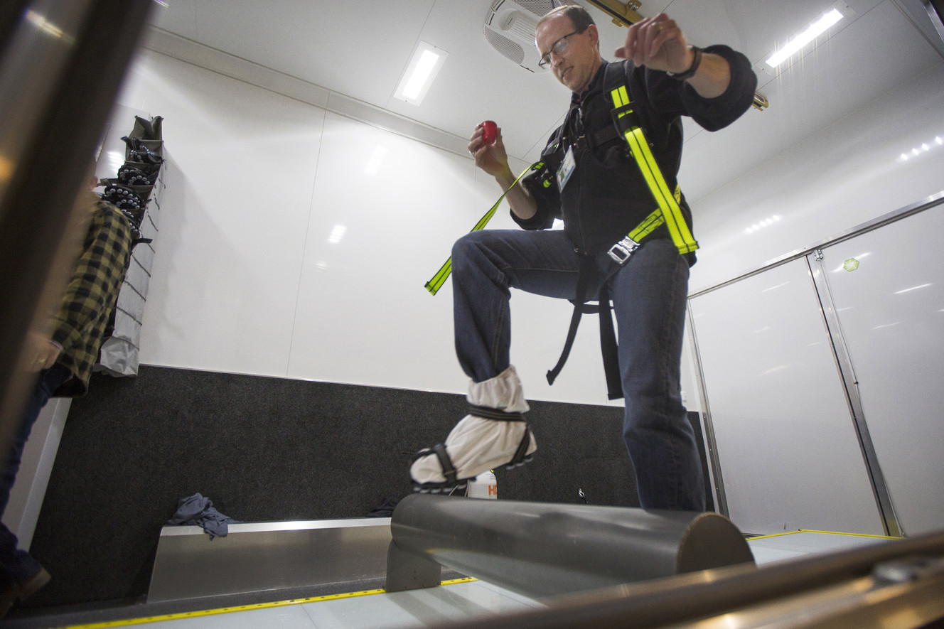 Jared Stradley, a Dominion Energy supervisor, tries to maintain his balance and not spill a cup of liquid while using the slip simulator at the company's headquarters in Salt Lake City on Monday, April 30, 2018. Cory Palmer, a senior safety specialist with Dominion Energy, said the slip simulator is designed to teach employees techniques for walking on slick surfaces. (Photo: Jacob Wiegand, KSL)