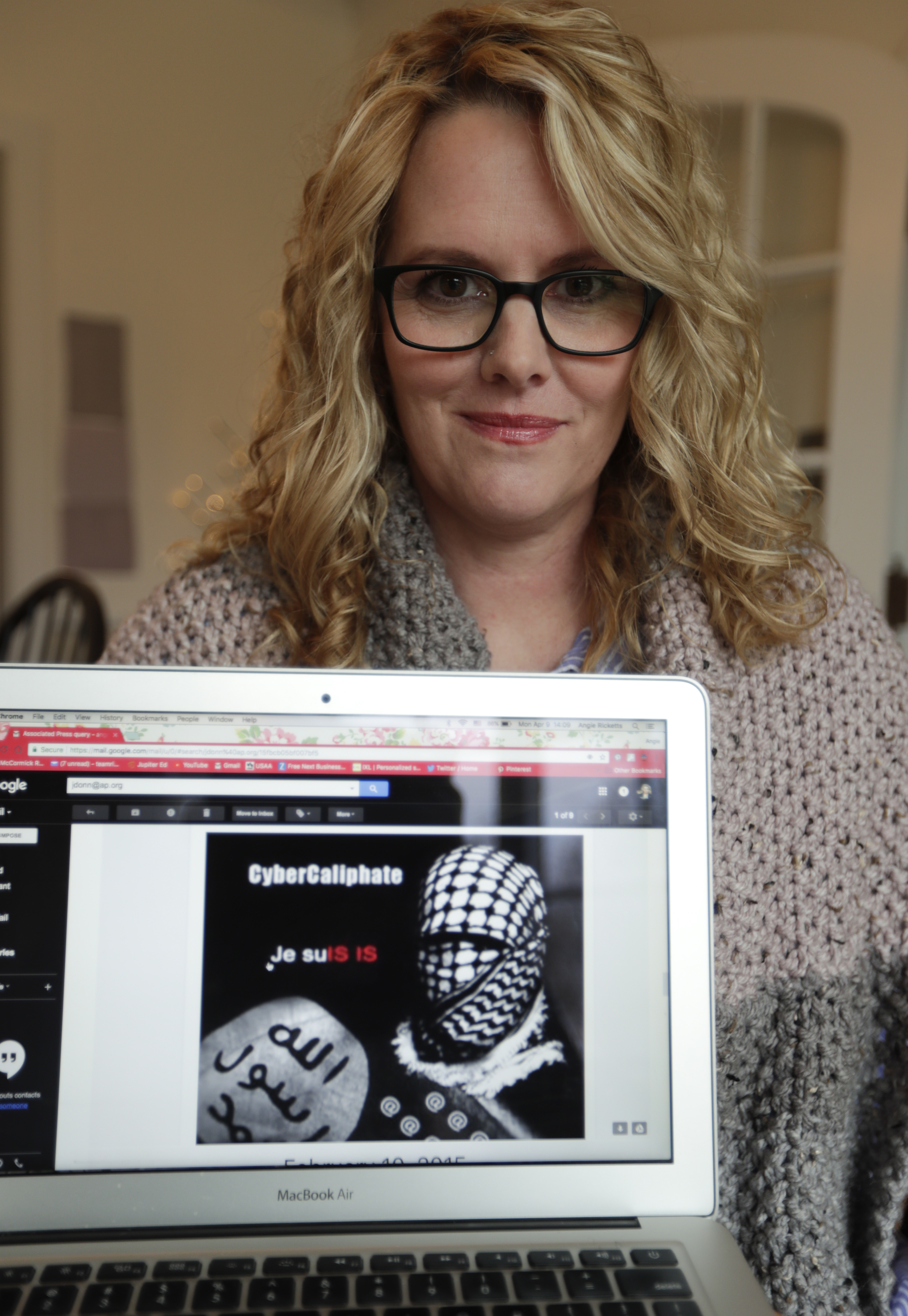 In this Monday, April 9, 2018, photo, Angela Ricketts poses with a screen shot of a message she received from a group claiming to be Islamic State supporters, in Bloomington, Ind. Russian spies masqueraded as Islamic State supporters to threaten vocal spouses of U.S. military personnel, including Ricketts, The Associated Press has found. (Michael Conroy, AP Photo)