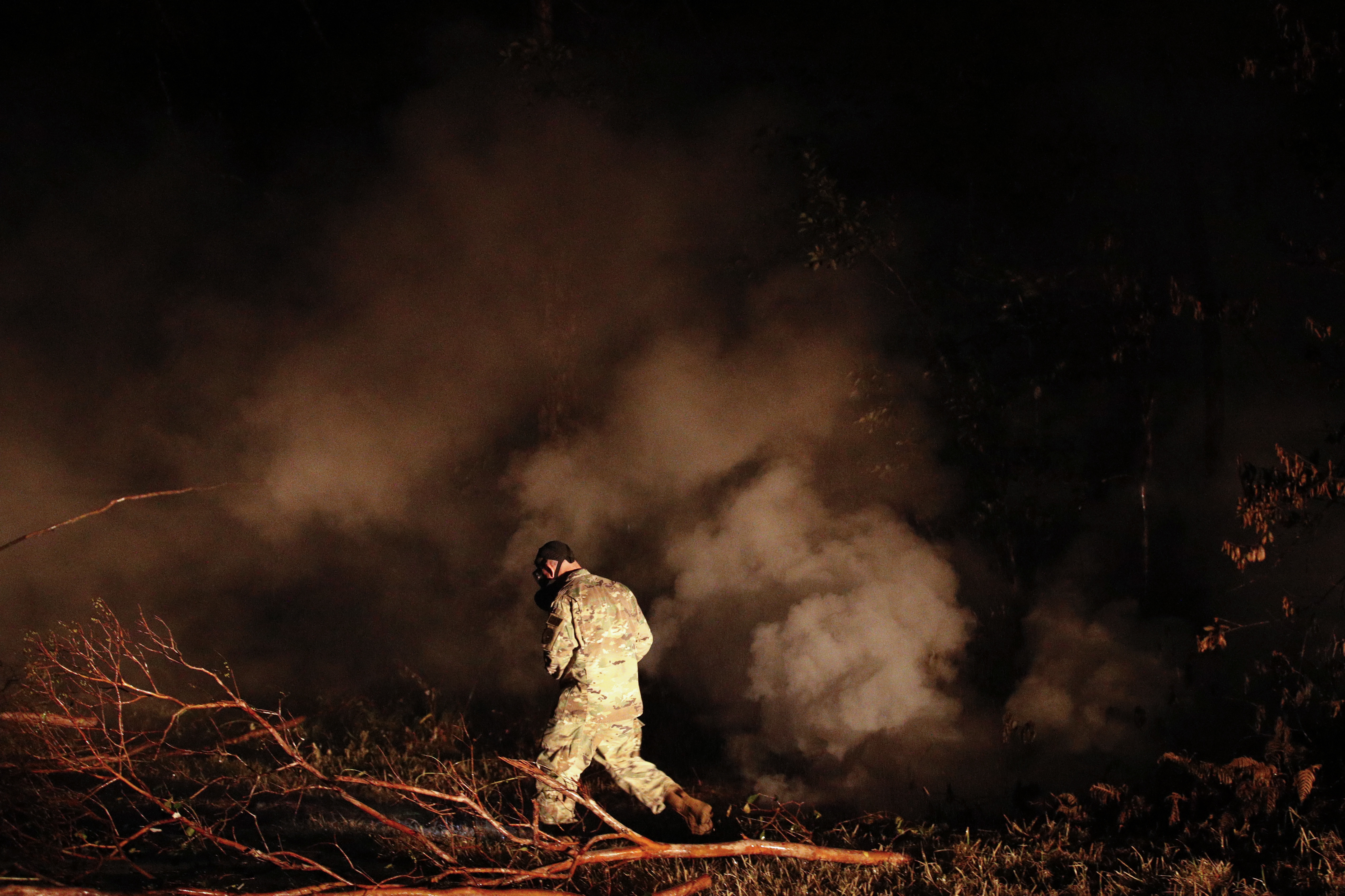 Sgt. 1st Class Carl Satterwaite, of the U.S. National Guard, tests air quality near cracks emitting volcanic gases from a lava flow in the Leilani Estates subdivision near Pahoa, Hawaii Thursday, May 10, 2018. Kilauea has destroyed more than 35 structures since it began releasing lava from vents about 25 miles (40 kilometers) east of the summit crater. (Jae C. Hong, AP Photo)