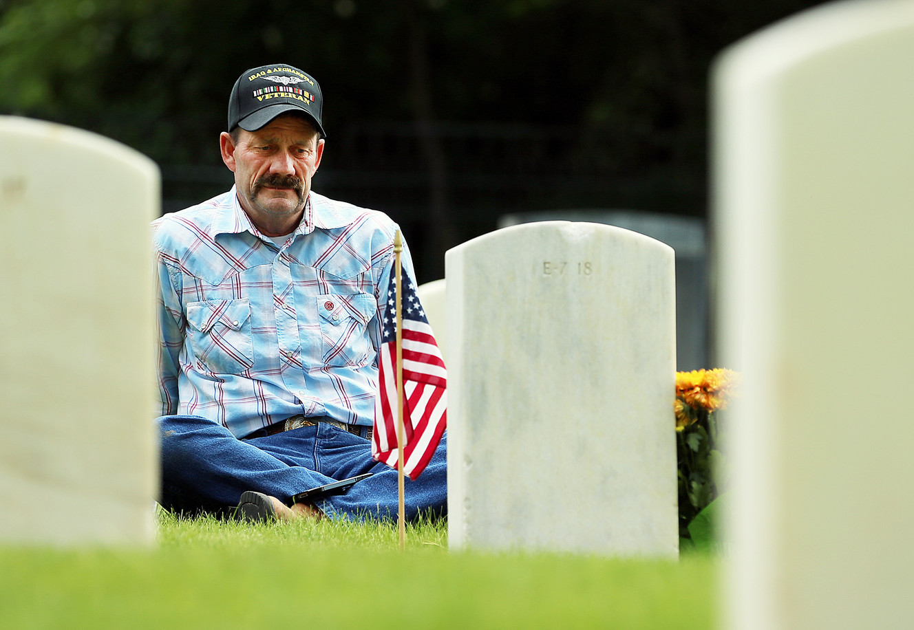 A veteran sits at the grave of his brother at Fort Douglas Military Cemetery on Monday, May 28, 2018. (Photo: Scott G Winterton, KSL)