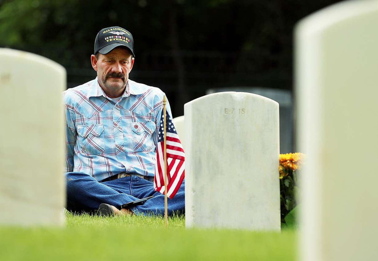 A veteran sits at the grave of his brother at Fort Douglas Military Cemetery on Monday, May 28, 2018. (Photo: Scott G Winterton, KSL)