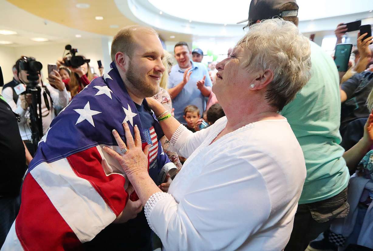 Josh Holt's grandmother Linda Holt drapes an American flag around him as he and his wife Thamy are swarmed by family and friends at the International Terminal in Salt Lake City International Airport on Monday, May 28, 2018. (Photo: Scott G Winterton, KSL)