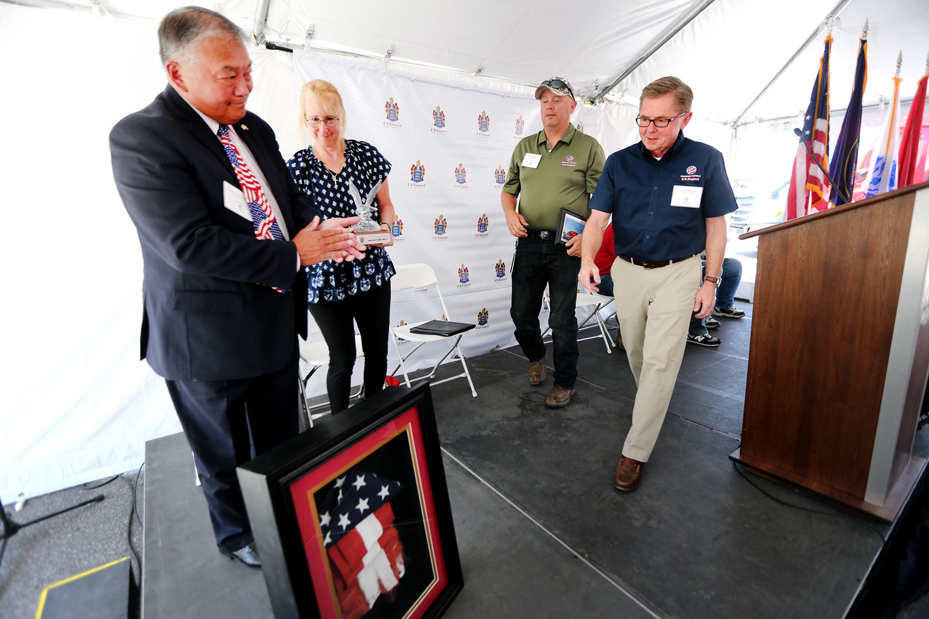 Retired U.S. Marine Corps Col. Rayfel Bachiller, left, presents C.R. England Chairman Dan England, right, a flag that flew over the U.S.S. Arizona at Pearl Harbor during a ceremony recognizing four drivers who are now part of the firm's Honored Veterans Fleet in West Valley City on Friday, June 8, 2018. (Photo: Scott G Winterton, KSL)