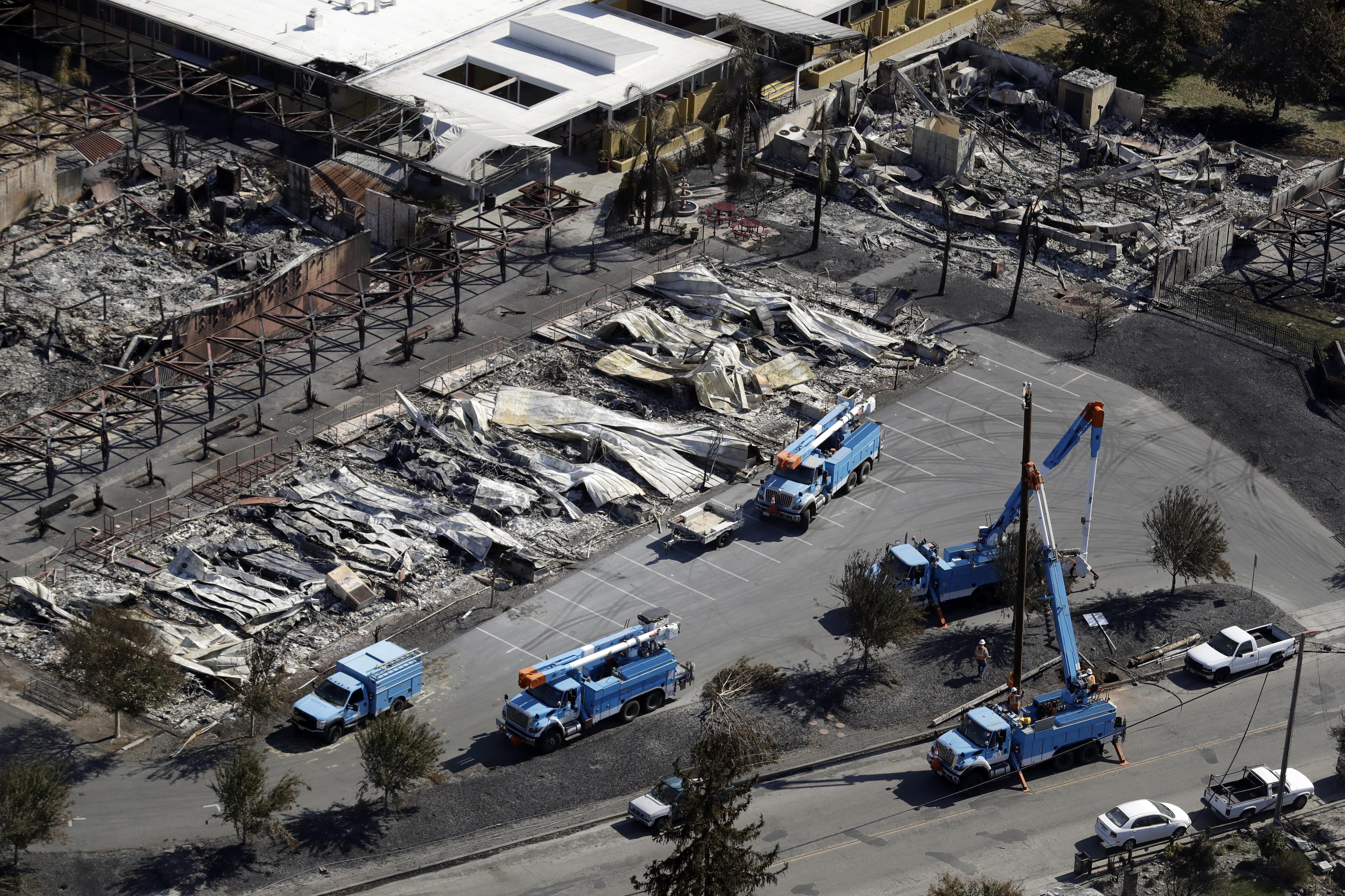 In this Oct. 14, 2017 file photo, PG&E crews work on restoring power lines in a fire ravaged neighborhood in an aerial view in the aftermath of a wildfire in Santa Rosa, Calif. Downed power lines caused a dozen Northern California wildfires last fall, including two that killed a total of 15 people, California's Department of Forestry and Fire Protection said Friday, June 8, 2018. The wildfires were part of a series that were the deadliest in California history. (AP Photo/Marcio Jose Sanchez, File)