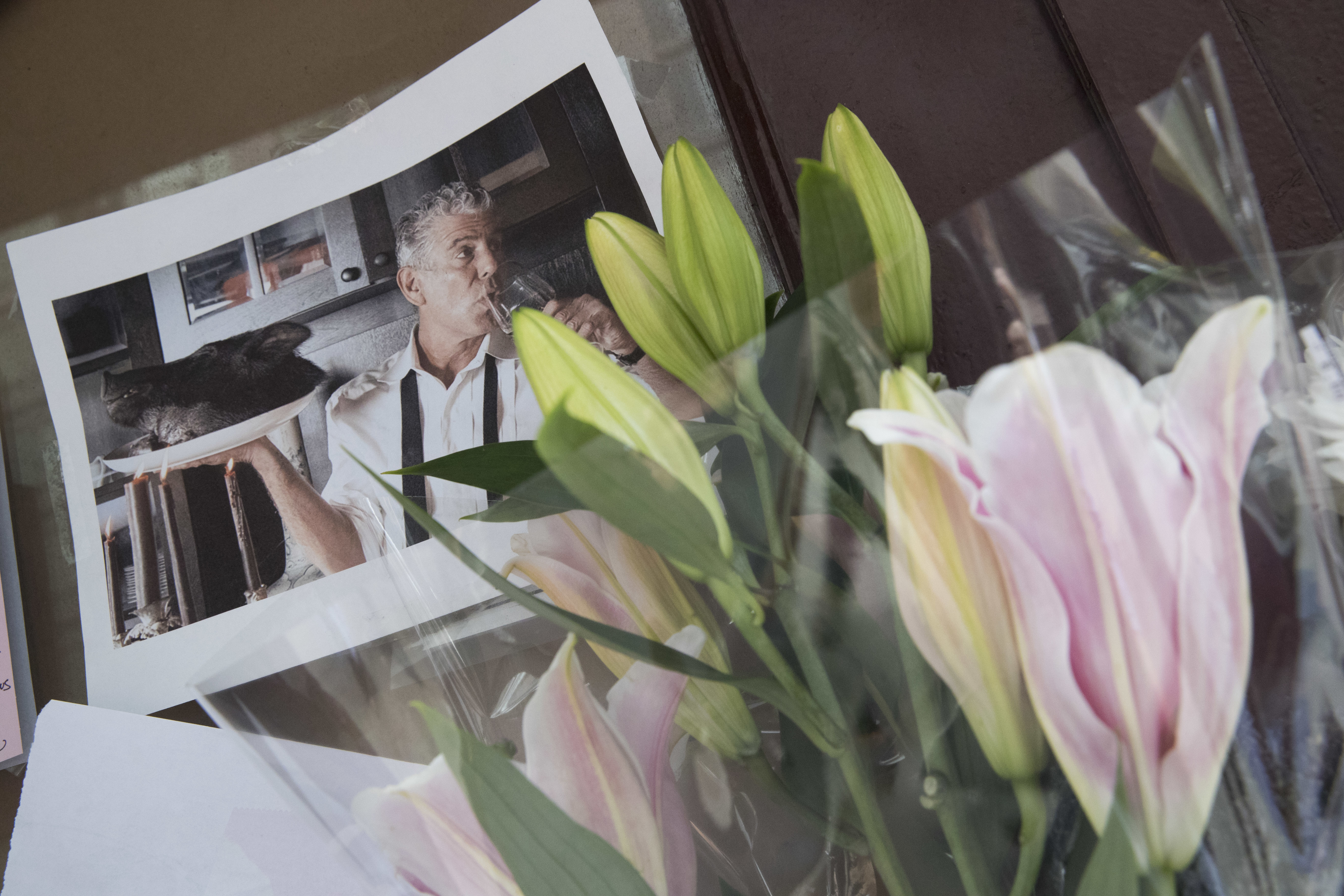 Flowers and a photo of Anthony Bourdain are seen at a make shift memorial outside the building that once housed Le Halles restaurant on Park Avenue, Friday, June 8, 2018, in New York. Bourdain, the celebrity chef and citizen of the world who inspired millions to share his delight in food and the bonds it created, was found dead Friday in his hotel room in France while working on his CNN series on culinary traditions. He was 61. (AP Photo/Mary Altaffer)