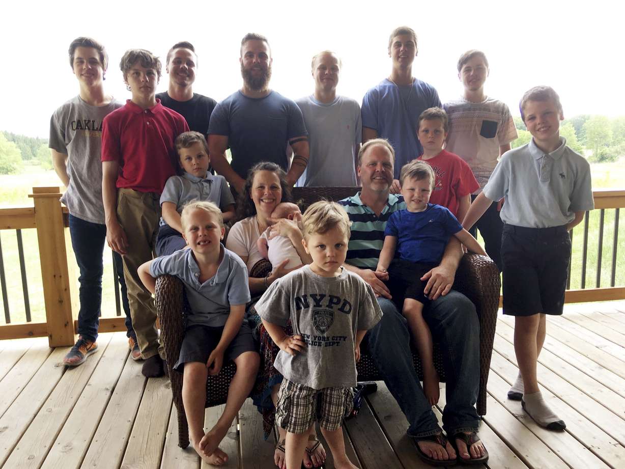 In a photo from May 30, 2018, the Schwandt family poses for a photo at their farm in Lakeview, Mich. Standing from left are Tommy, Calvin, Drew, Tyler, Zach, Brandon, Gabe, Vinny and Wesley. Seated, starting at upper left are Charlie, Luke, mother Kateri holding Finley, father Jay with Tucker and Francisco in the foreground. The 14-boy family ranges in age from 2 months to 25 years. And no girls. (Mike Householder, AP Photo)