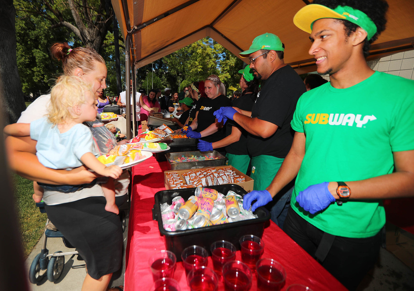 Rose Fotter and daughter Eternity Fotter get food from Avery Anderson during Subway's 10th annual Day of Giving at Pioneer Park in Salt Lake City on Tuesday, June 19, 2018. (Photo: Scott G Winterton, KSL)