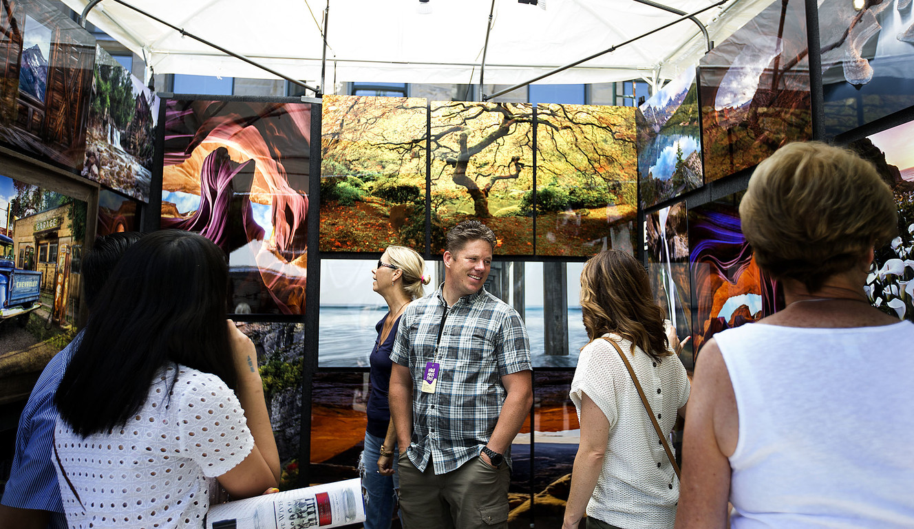 Photographer Ryan Smith, center, speaks to people about his work at the Utah Arts Festival in Salt Lake City on Friday, June 22, 2018. (Photo: Laura Seitz, KSL)