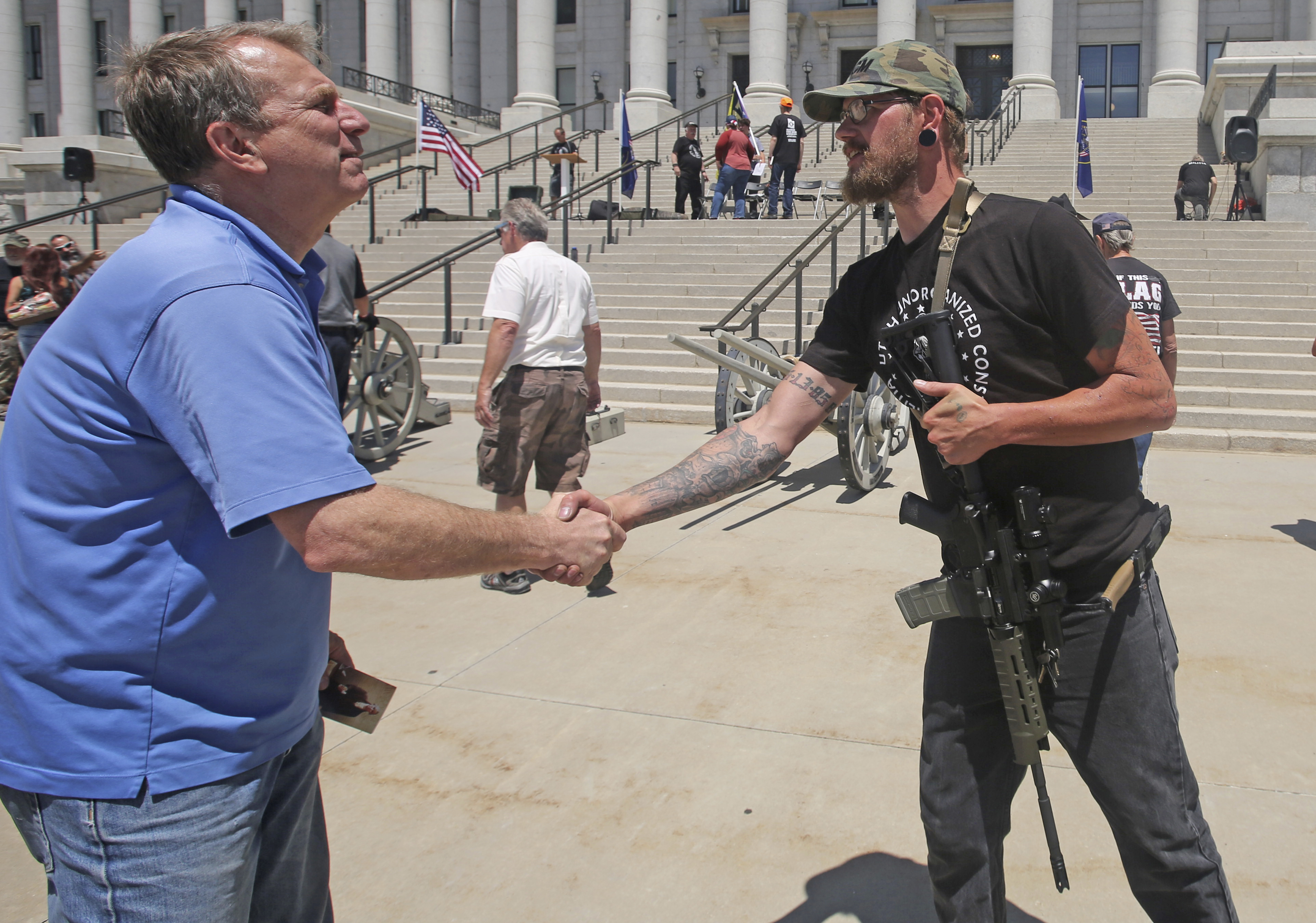 In this June 16, 2018, photo, Chris Herrod shakes hands with Kevin Orton during a 2nd amendment rally at the Utah State Capitol, in Salt Lake City. U.S. Rep. John Curtis looking to take a major step toward winning his first full term in Congress in Utah's 3rd District. He won a special election to finish Rep. Jason Chaffetz's term months ago, and is now facing a rematch against former state lawmaker Herrod. (AP Photo/Rick Bowmer)